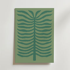 Quiet Palm Poster från Bozetto föreställer en minimalistisk stiliserad ormbunke med mörkgröna symmetriska grenar på en dovt grön bakgrund, inramad och placerad mot en ljus vägg.
