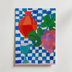 Bozetto "Table of Joy Poster" föreställer en röd vas, lila druvor, gröna blad och en blågrön bägare på en blåvitrutig bakgrund.
