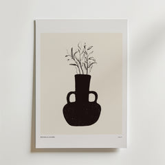 Rooted In Light Poster" från Bozetto föreställer en minimalistisk svart vas med två handtag och skira växtstjälkar på en beige bakgrund som ger jordnära inredning till en vit vägg.