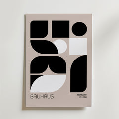 Bozetto Bauhaus Geometric Blocks Poster visar abstrakta svarta former på en beige matt yta, med "Bauhaus" längst ner till vänster och "AUSSTELLUNG 1919-1933" i små bokstäver på premiumpapper.