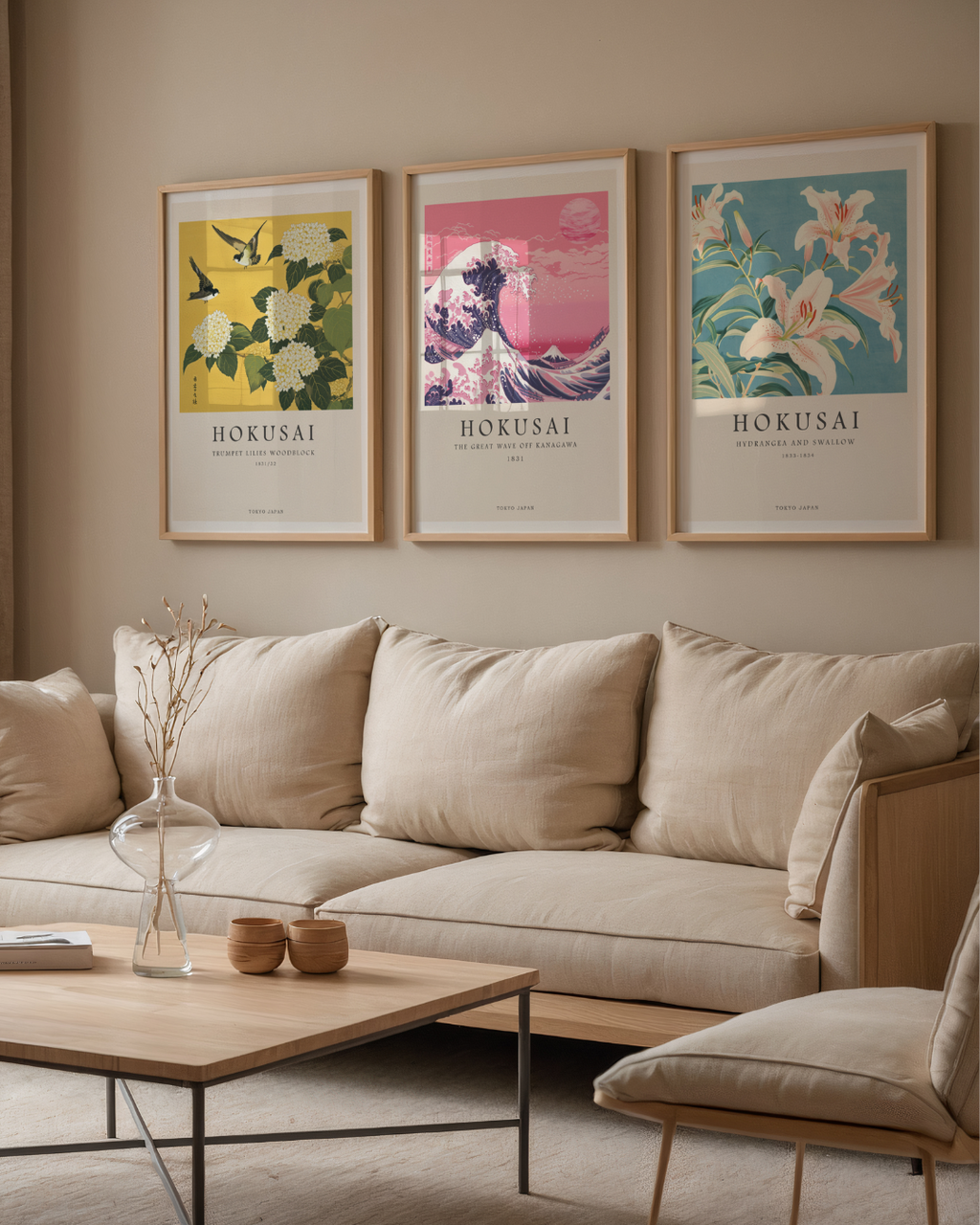 Ett mysigt vardagsrum med en beige soffa, soffbord i ljust trä och Bozettos Bundle 3-pack Hokusai No. 1-tavlor inramade ovanför. En glasvas med torkade grenar på bordet ger inredningen en japansk konstkänsla.