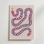 Playful Snake Art Poster från Bozetto föreställer en röd orm i popkonststil med blå och svarta ögon, blå triangulära piggar och en ljusrosa bakgrund - perfekt som grafisk konst eller en effektfull poster.