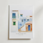 Santorini Silence Poster från Bozetto föreställer pastellblå och vita byggnader med kalkvita väggar, solblekta trappsteg och välvda dörröppningar. Inspirerad av Santorini, Grekland, visar den texten SANTORINI TRAVEL GALLERY nedan.