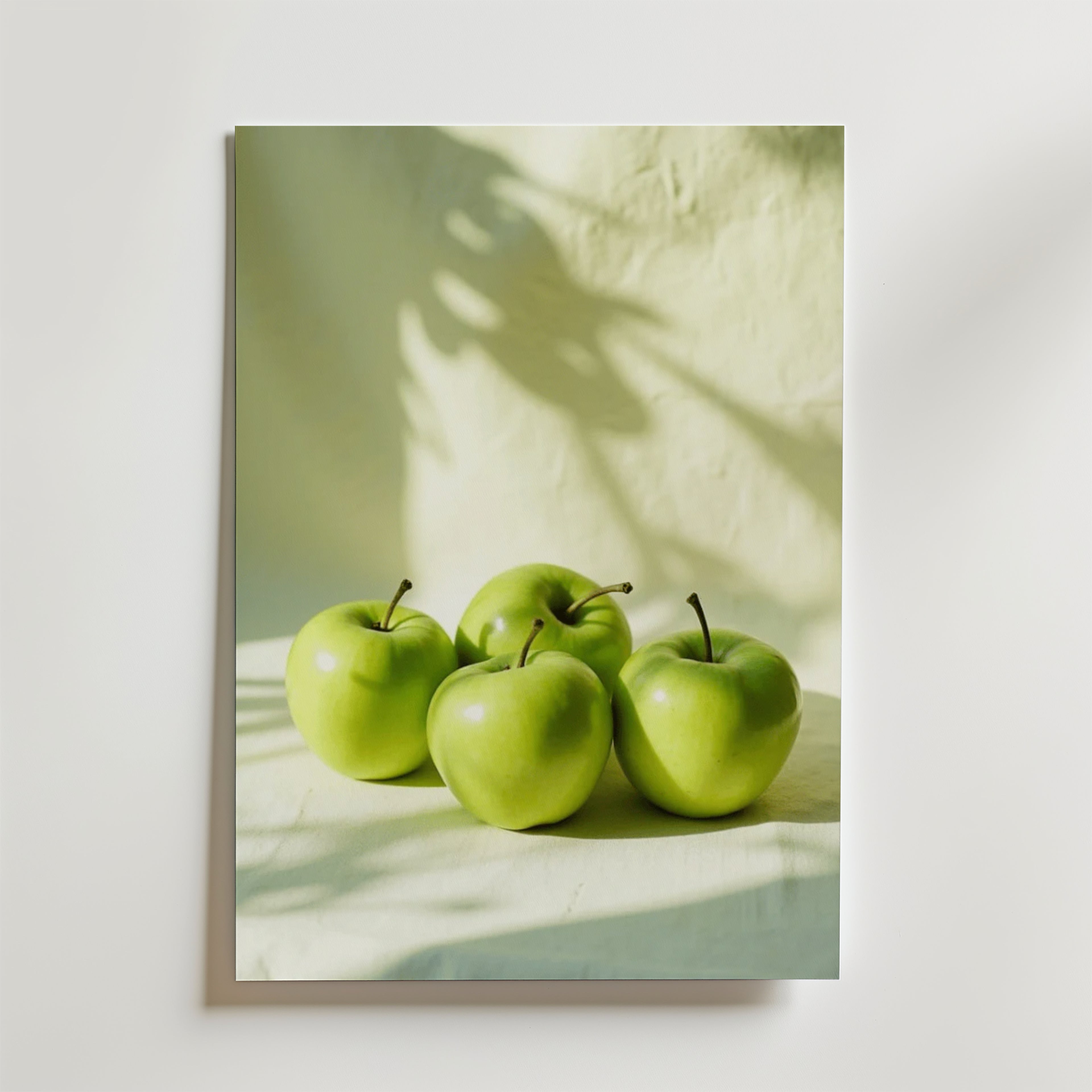 Green Apple Poster by Bozetto föreställer fyra gröna äpplen på en ljus yta med mjuka skuggor och en strukturerad ljus bakgrund, tryckt på FSC-certifierat premiumpapper med en lyxig matt yta.