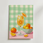 Bozetto Orange Citrus Cocktail Poster visar en citrusdrink med apelsinskivor, en hel apelsin, citronklyftor och frukt på en rosa yta, tryckt på premiumpapper med en matt finish och en grönvitrutig bakgrund.