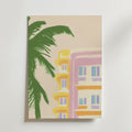 Bozetto Summer in the South Poster föreställer en art deco-byggnad med gula och rosa accenter bredvid en grön palm på en ljusbeige bakgrund, tryckt på premiumpapper med matt yta för en modern finish.