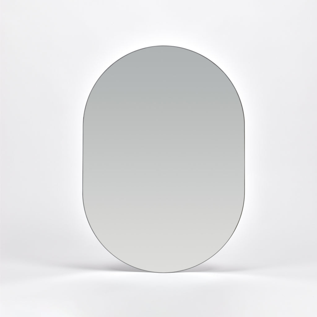 Bozetto Spegel Ark 50x70 cm, en stor ramlös väggspegel med en platt bas, är monterad på en vit vägg och reflekterar en mjuk neutral gradient.