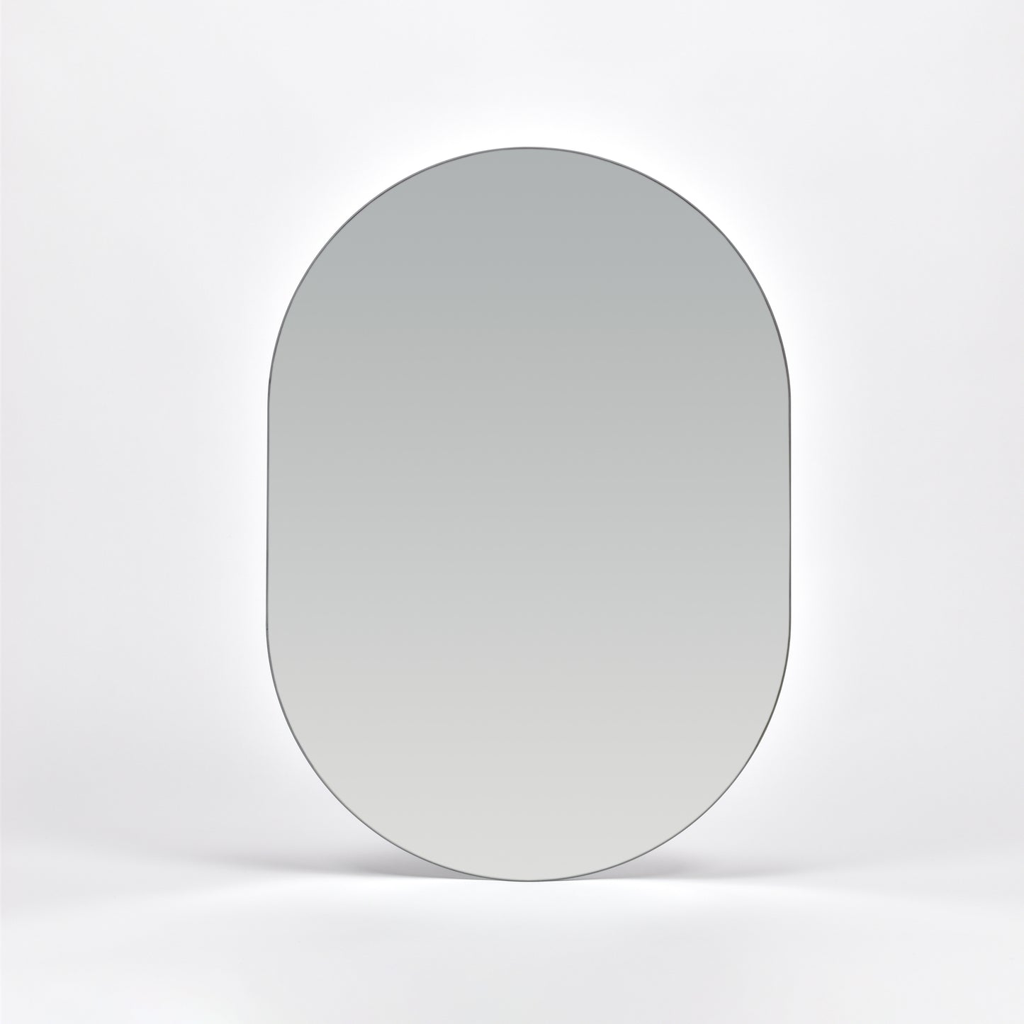 Bozetto Spegel Ark 50x70 cm, en stor ramlös väggspegel med en platt bas, är monterad på en vit vägg och reflekterar en mjuk neutral gradient.