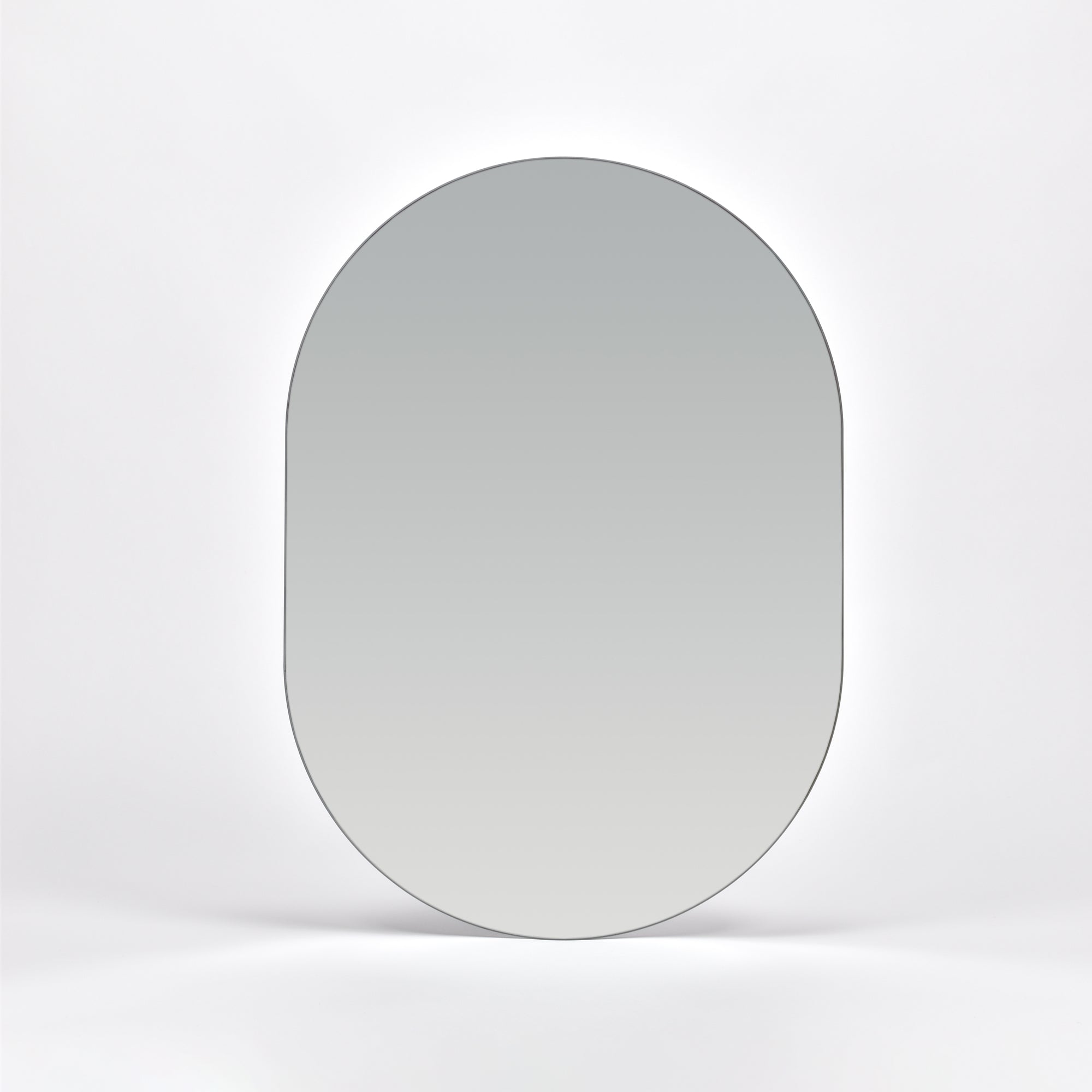 Bozetto Spegel Ark 50x70 cm, en stor ramlös väggspegel med en platt bas, är monterad på en vit vägg och reflekterar en mjuk neutral gradient.