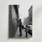 En man och en pojke står vid en tegelvägg med gatukonst, veteranbilar och byggnader bakom dem. Street Art Inspiration Poster by Bozetto är tryckt på premiumpapper och är FSC-certifierad - perfekt för ditt rum.