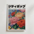 Spring Sonata Poster" från Bozetto har japansk text och en illustrerad bukett med rosor, prästkragar och pioner på en vit bakgrund och fångar charmen hos ett blommigt tidningsomslag eller en elegant blomsterkonst.