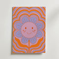 Bozetto Smiling Flower Poster föreställer en glad blomma med lila kronblad och orange kinder på en livlig orange och rosa vågig bakgrund - perfekt för lekfull 70-talsinspirerad inredning eller som en unik touch i barnrummet.