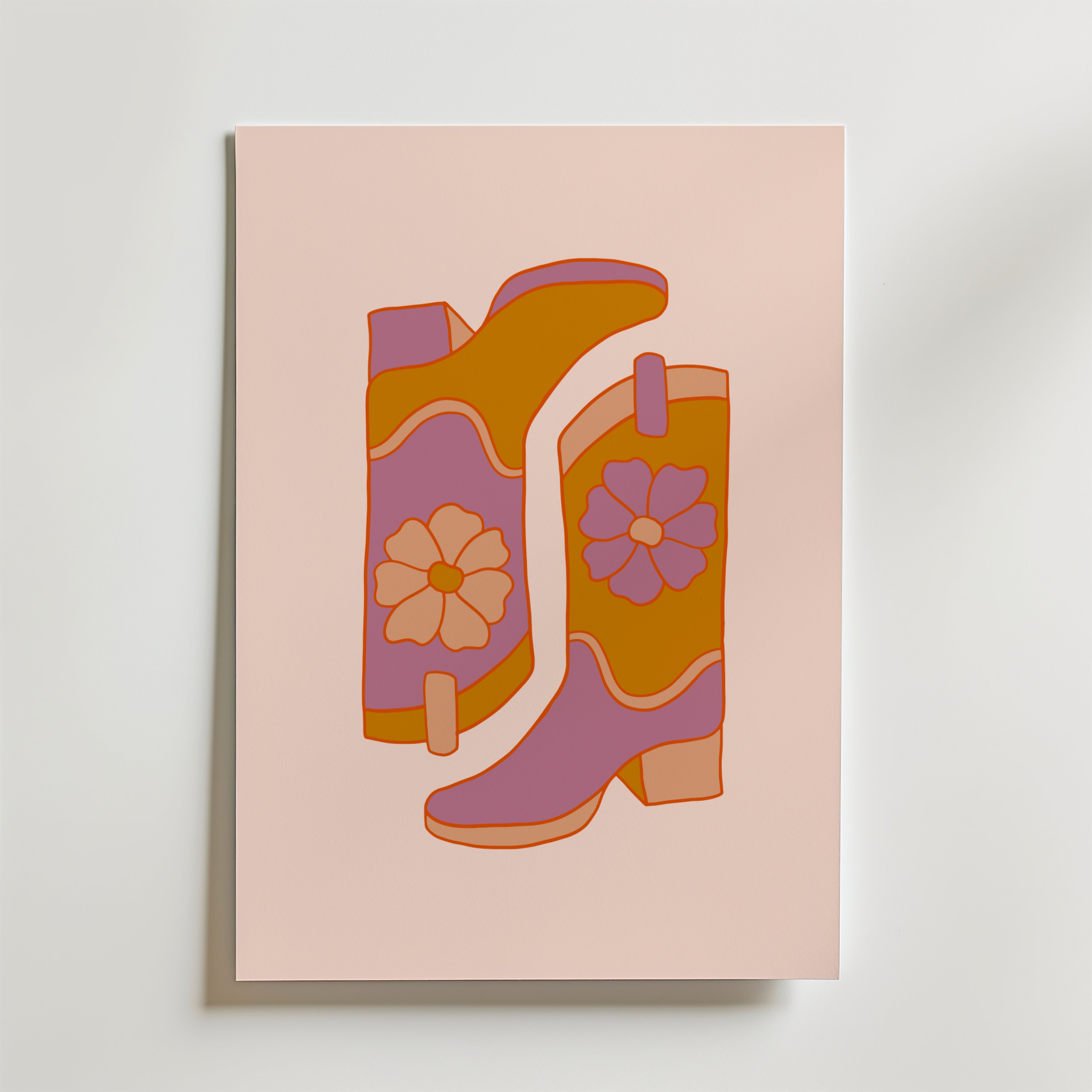 Bozettos "Boots and Blooms Poster" föreställer två blommiga stövlar i orange, rosa och lila med djärva blommönster mot en ljusrosa bakgrund.
