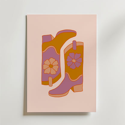 Bozettos "Boots and Blooms Poster" föreställer två blommiga stövlar i orange, rosa och lila med djärva blommönster mot en ljusrosa bakgrund.