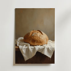 Sourdough Bread Loaf Poster by Bozetto visar ett rustikt bröd på ett träbord med en vit duk, mjukt upplyst mot en neutral bakgrund - tryckt på premiumpapper för en elegant finish.