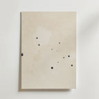 Postern Abstract Beige No.2 Poster by Bozetto har ett off-white premiumpapper med små, oregelbundna svarta bläckfläckar på den matta ytan, fotograferat mot en vit bakgrund.