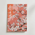 Bozetto Japanese Cherry Blossom Poster har illustrerade körsbärsblommor på rosa grenar mot en korallfärgad bakgrund, som för tankarna till en japansk inredningsstil med vit och orange japansk text bredvid och ovanför blommorna.