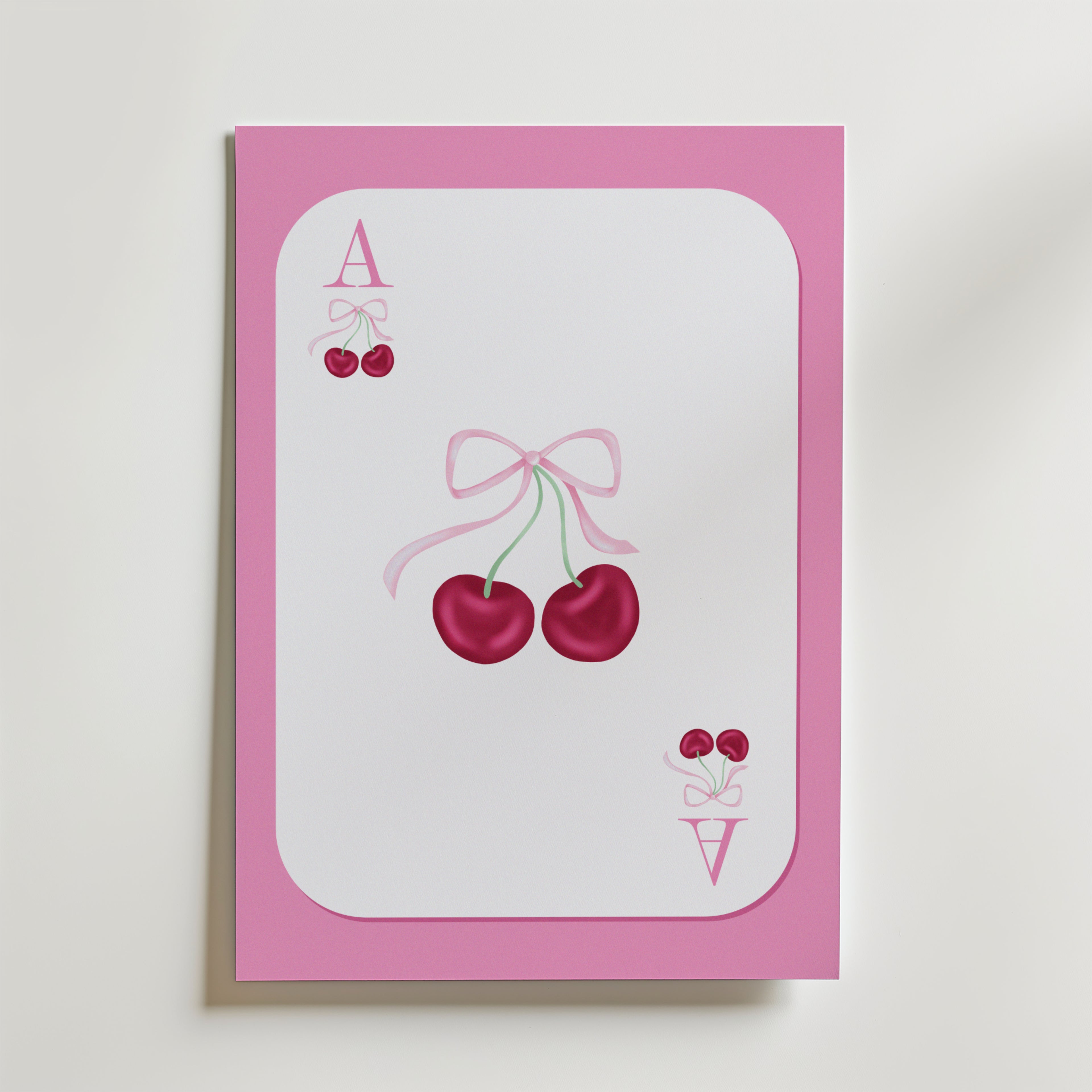 Ace of Cherries Poster by Bozetto föreställer ett spelkort med en rosa kant, två körsbär i mitten som är bundna med ett rosa band och små körsbär bredvid bokstäverna A och V i hörnen.
