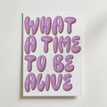 What a Time Poster by Bozetto har en fet, glansig lila text som säger WHAT A TIME TO BE ALIVE i bubblande typografi på en vit bakgrund - en upplyftande poster som ger glädje till ditt hem.