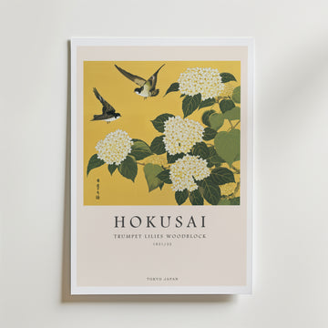 Affischen Yellow Botanical Harmony Poster från Bozetto visar Hokusais träsnitt med trumpetliljor, vita blommor, gröna blad och två fåglar på en guldfärgad bakgrund med text: HOKUSAI Trumpetliljor Träsnitt 1831/32 Tokyo Japan.