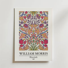 Bozetto William Morris Hyacinth Poster har en livfull blommig design med detaljerade blad och hyacintblommor i rött, rosa, orange och grönt. Under konstverket finns orden: William Morris, Hyacinth, 1887.
