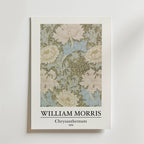 Bozetto William Morris Chrysanthemum Poster visar den intrikata blomsterdesignen från 1876 i mjukt grönt, krämfärgat och blått på en himmelsblå bakgrund med texten "WILLIAM MORRIS Chrysanthemum 1876" under bilden.