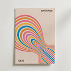 Bozetto Bauhaus Flow Poster med titeln "BAUHAUS 1919" visar levande orange, rosa, blå och gula färgband som bildar ett dynamiskt abstrakt mönster i Bauhaus-stil på en beige bakgrund.