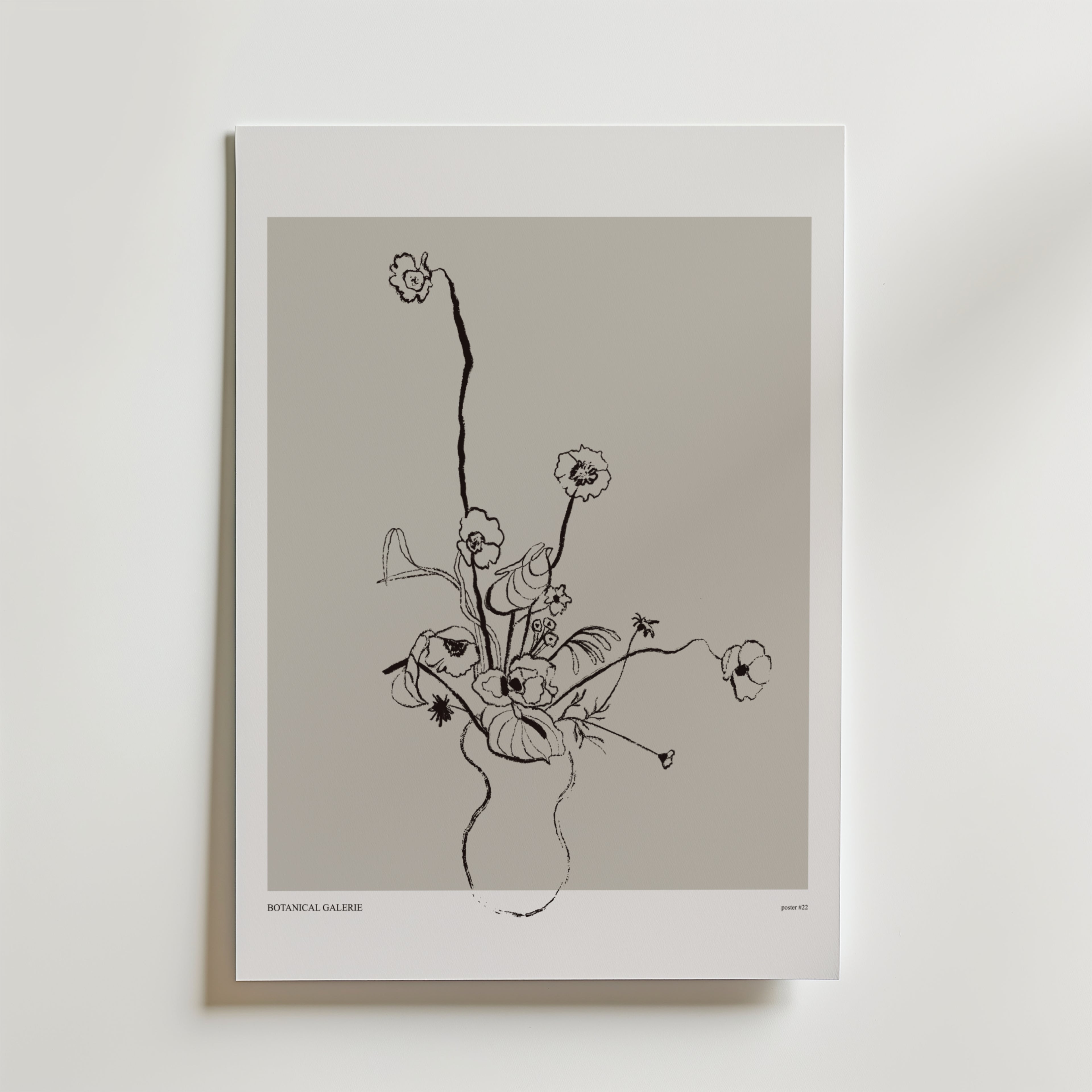 Floral Reverie Poster" från Bozetto föreställer minimalistiska blommor i en vas med svarta linjer på en neutral grå bakgrund, inramad av en vit kant. Denna eleganta poster tillför modern stil och raffinerad blomsterkonst till din inredning.