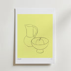 Postern Sunlight On Stillness från Bozetto har en minimalistisk linjeteckning av en kanna, en skål och ett äpple på en guldfärgad bakgrund. Denna eleganta poster visas med en vit matta och ger en lugn stil till alla utrymmen.